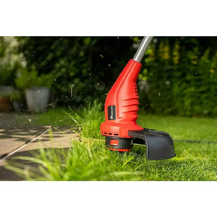 Hurricane Elektro-Rasentrimmer HERT-I-3025 - 300 W, Schnittbreite Faden: 25 cm - Eine rote Hurricane-Gartentrimmer schneidet Gras an einer hölzernen Terrassenkante. Ideal für präzise Gartenarbeit und Rasenpflege.