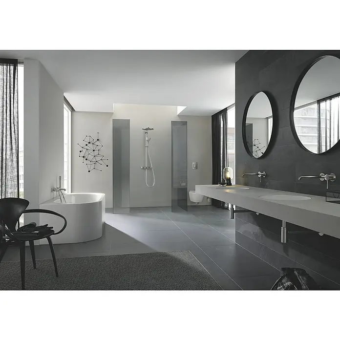 Grohe Essence Badewannenarmatur - Ausladung Armatur: 193 mm, Supersteel, Matt - Elegantes Badezimmerdesign mit runden Spiegeln über einem modernen Waschtisch, einer freistehenden Badewanne und dunklen Akzenten für ein stilvolles Ambiente.