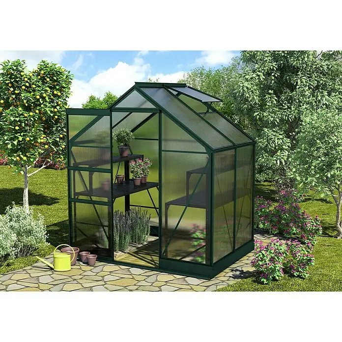 Vitavia Gewächshaus Apollo 2500 - Außenmaß inkl. Dachüberstand (B x T): 195 x 137 cm, 6 mm, Smaragd - Das Bild zeigt ein Gewächshaus mit Regalen, auf denen verschiedene Pflanzen in Töpfen stehen, umgeben von einem Garten mit Bäumen und Blumen.