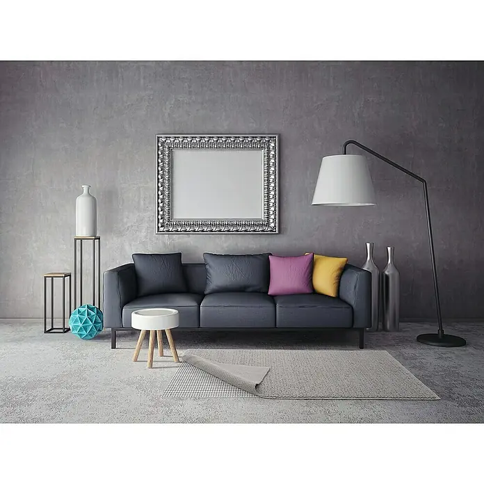 D-c-fix Teppichgleitschutz Loom - 180 x 120 cm - Ein modernes Wohnzimmer mit grauem Sofa, bunten Kissen, einer Stehlampe und dekorativen Elementen vor einer grauen Wand.
