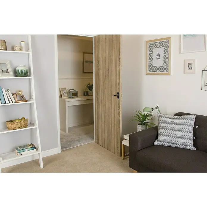 D-c-fix Holzoptikfolie Sonoma Eiche - 210 x 90 cm, Hell, Selbstklebend - Helle Holztür in einem Zimmer, die zu einem kleinen Arbeitsbereich führt. Die Tür ist ein zentrales Element der Inneneinrichtung.