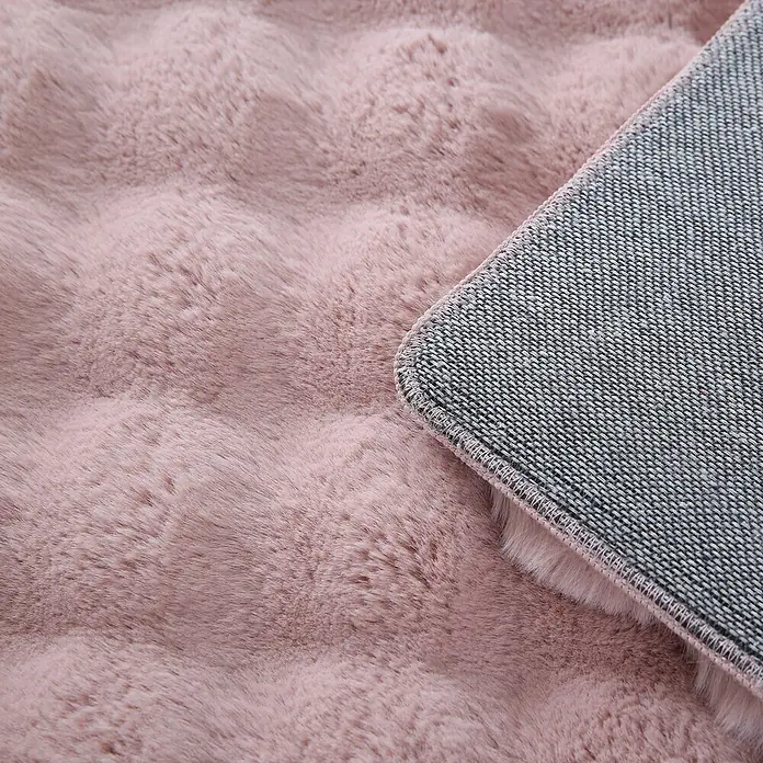 Fellteppich Ambiance - Rosa, 170 x 120 cm, 100 % Polyester - Nahaufnahme eines flauschigen, rosa Teppichs mit rutschfester Unterseite, ideal für gemütliche Wohnbereiche.