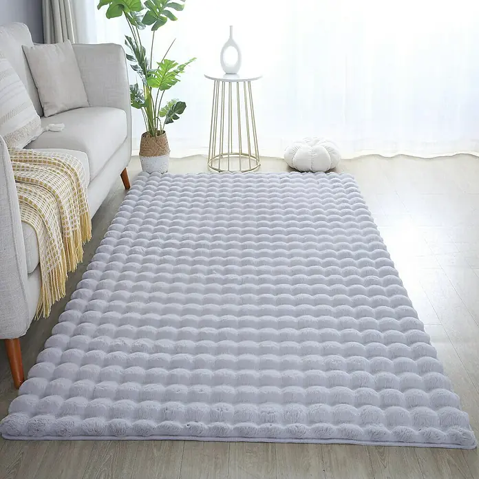Fellteppich Ambiance - Silber, 250 x 80 cm, 100 % Polyester - Ein weicher, hellgrauer Teppich mit Noppenstruktur liegt in einem hellen Wohnzimmer und sorgt für eine gemütliche Atmosphäre.