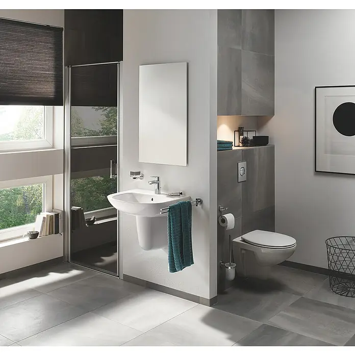 Grohe BauFlow Waschtischarmatur S-Size mit Energie-Sparfunktion - Chrom, Glänzend - Modernes Badezimmer mit weißem Waschbecken, Toilette und grauen Fliesen. Das schlichte Design schafft eine elegante Atmosphäre.