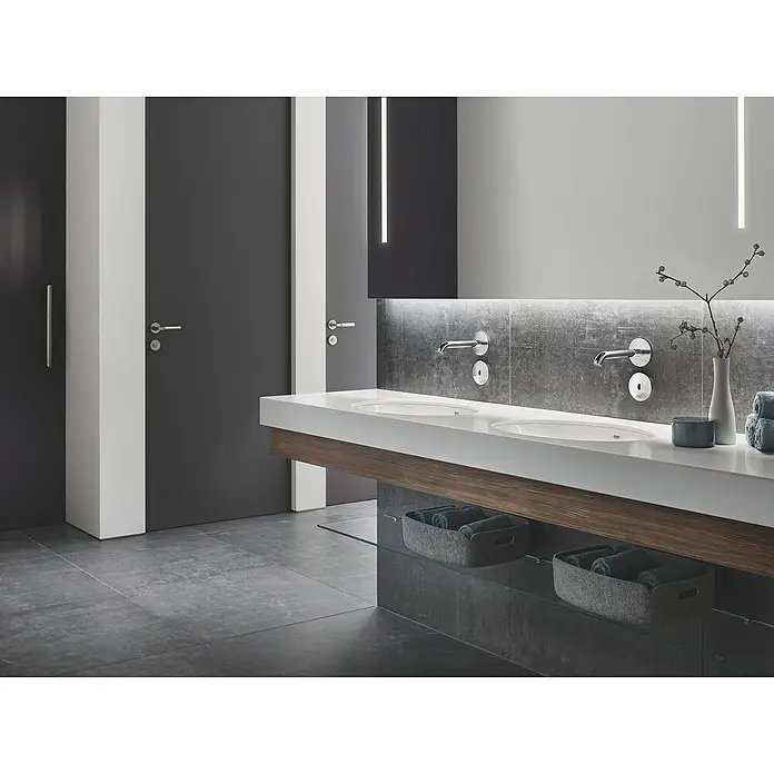 Grohe Essence Waschtischarmatur E - Wandmontage, Chrom, Glänzend, Ausladung Armatur: 182 mm - Helles Badezimmer mit Doppelwaschbecken, Holzelementen, grauen Akzenten und zwei Türen, die ein modernes und stilvolles Ambiente schaffen.