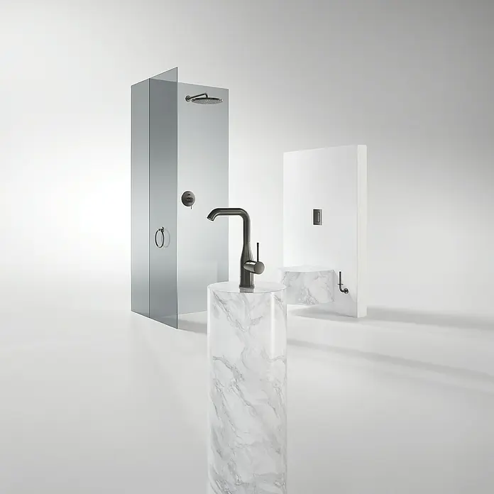Grohe Essence New Waschtischarmatur L-Size - Mit Zugstange, Hard Graphite, Matt - Ein Badezimmer mit einer modernen Dusche, einem Waschbecken mit Marmorsockel und Armaturen in dunklem Metall.