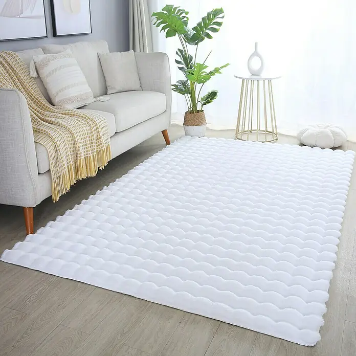 Fellteppich Ambiance - Weiß, 250 x 80 cm, 100 % Polyester - Ein weißer, flauschiger Teppich mit Wellenmuster liegt in einem Wohnzimmer mit Sofa, Pflanze und Beistelltisch. Der Teppich ist das Highlight.