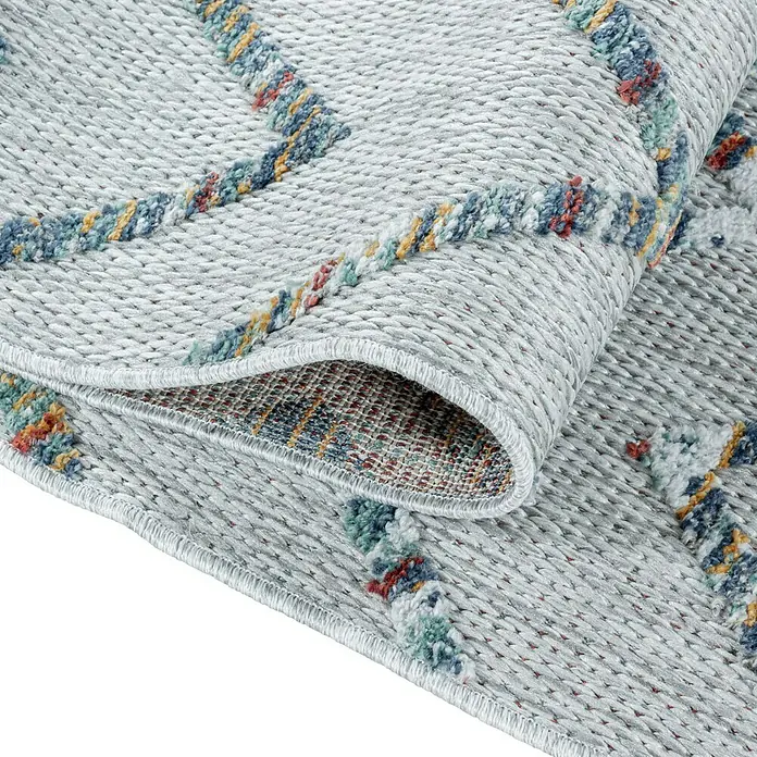 Outdoor-Teppich Bahama IV - Multi, 200 x 140 cm, 100 % Polypropylen - Detailansicht eines hellgrauen Teppichs mit farbigen Akzenten und hochgeklappter Ecke, der die Textur und Verarbeitung hervorhebt.