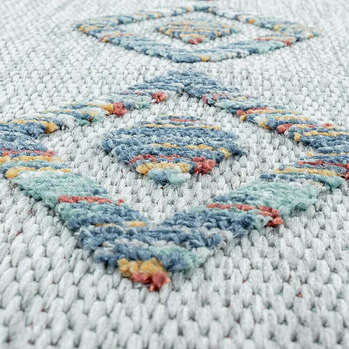 Outdoor-Teppich Bahama IV - Multi, 200 x 140 cm, 100 % Polypropylen - Detailaufnahme eines strukturierten Teppichs mit geometrischen Mustern in Blau-, Gelb- und Rottönen auf einem weißen Grund.