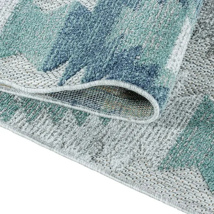 Outdoor-Teppich Bahama I - Blau, 200 x 140 cm, 100 % Polypropylen - Nahaufnahme eines Teppichs mit abstraktem blau-grauem Muster und umgeschlagener Ecke, der seine Textur und Verarbeitung zeigt.