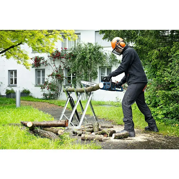 Bosch Professional AMPShare 18V Akku-Kettensäge GKE 18V-40 - 18 V, Li-Ionen, Ohne Akku, Schwertlänge: 40 cm - Holzarbeiter mit Bosch-Kettensäge beim Zerkleinern von Ästen auf einem Sägebock. Sicherheit wird durch Helm und Visier gewährleistet.