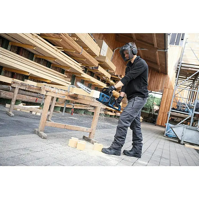Bosch Professional AMPShare 18V Akku-Kettensäge GKE 18V-40 - 18 V, Li-Ionen, Ohne Akku, Schwertlänge: 40 cm - Ein Mann mit Schutzausrüstung sägt Holz mit einer blauen Bosch Akku-Kettensäge. Die Kettensäge ist ideal für Holzarbeiten im Innen- und Außenbereich.