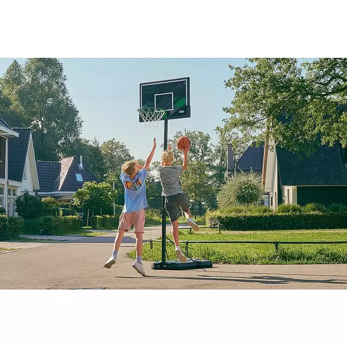 Salta Basketballkorb Forward - L x B x H: 172 x 110 x 362 cm, Schwarz - Zwei Jungen spielen Basketball mit einem schwarzen Salta-Basketballkorb mit grünen Akzenten. Einer wirft, der andere verteidigt.