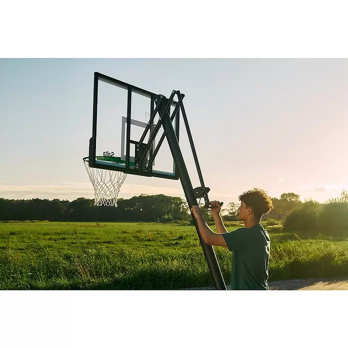 Salta Basketballkorb Guard - Schwarz, Höhe: 371 cm - Eine Person verstellt die Höhe eines schwarzen, grünen, tragbaren Basketballkorbs im Freien.