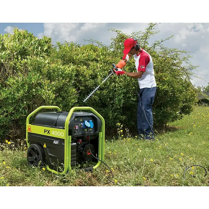 Pramac Stromerzeuger PX4000 - 2,3 kW, Tankvolumen: 18,5 l, Verbrauch: 1,29 l/h - Ein Prasac PX 4000 Generator steht im Freien, während ein Mann eine Heckenschere benutzt.