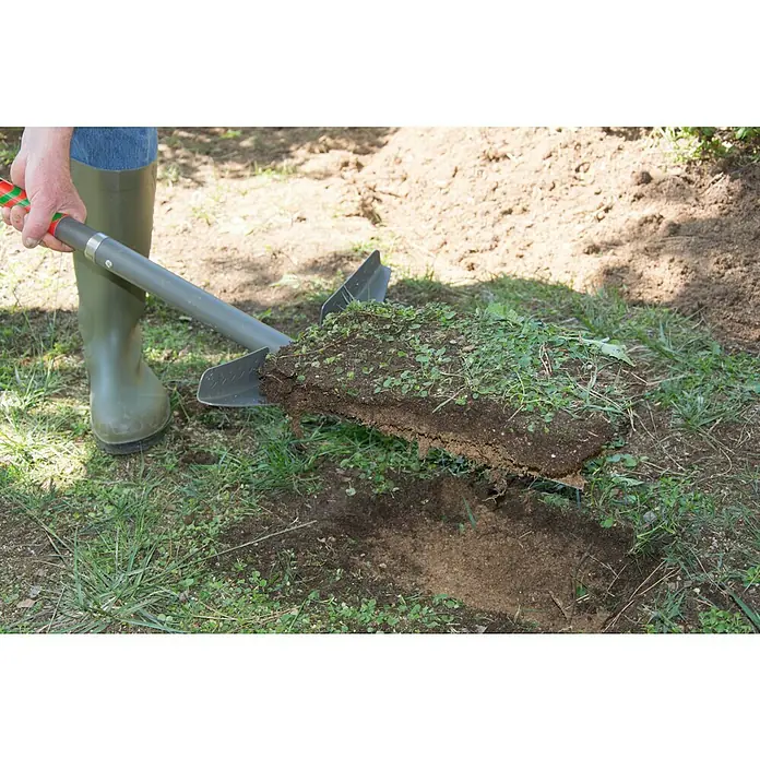 Starlyf Multifunktionsspaten Root Digger - 114 cm, Stahl - Eine Person mit Gummistiefeln benutzt einen Spaten, um Erde auszugraben. Der Spaten ist ein Gartengerät, das beim Umgraben hilft.