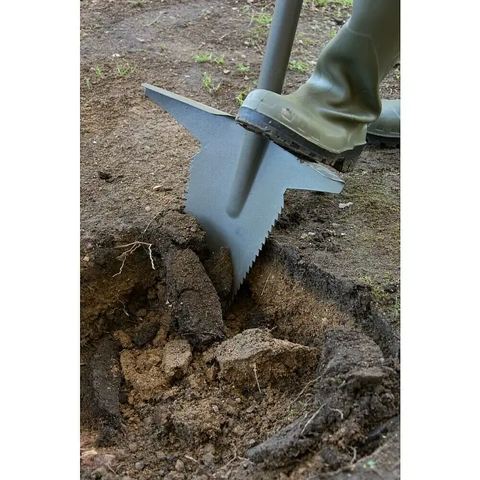 Starlyf Multifunktionsspaten Root Digger - 114 cm, Stahl - Ein Spaten mit Sägezähnen wird mit einem Gummistiefel in den Boden getrieben, um ein Loch zu graben.