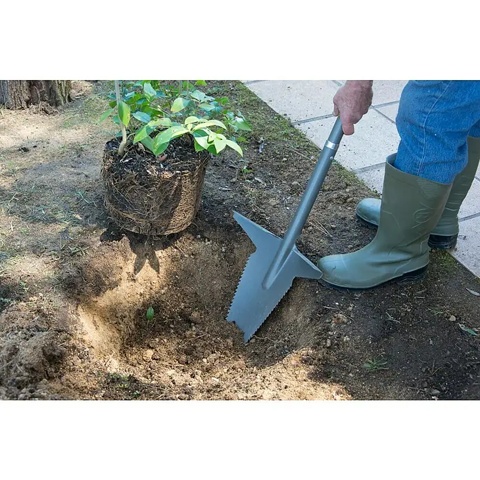 Starlyf Multifunktionsspaten Root Digger - 114 cm, Stahl - Eine Person pflanzt mit einem Spaten und grünen Gummistiefeln einen Setzling in ein Erdloch.