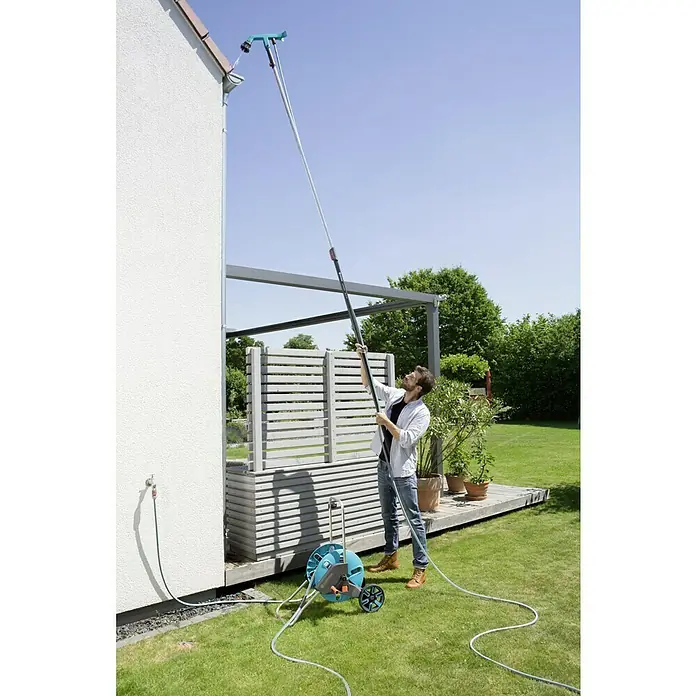 Gardena Combisystem Dachrinnenreiniger - Passend für: Gardena Combisystem Stiele - Ein Mann benutzt eine Gardena Dachrinnenbürste, um eine Dachrinne zu reinigen. Die Bürste ist an einem Teleskopstiel befestigt und wird von einem Schlauch gespeist.