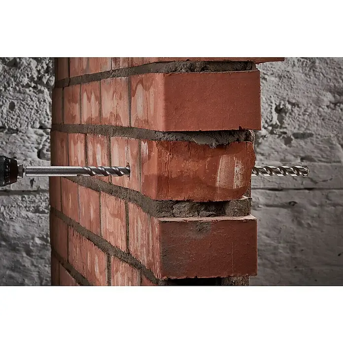 Wolfcraft Beton- & Steinbohrer Mauerdurchbruchsbohrer - Durchmesser Bohrer: 12 mm - Nahaufnahme einer Bohrmaschine, die ein Loch in eine rote Ziegelwand bohrt, wobei der Bohrer deutlich sichtbar ist.