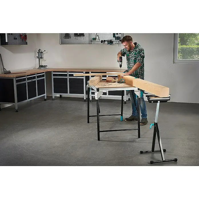 Wolfcraft Multifunktions-Auflagebock - Arbeitshöhe: 630 mm - 1.000 mm, Belastbarkeit: 50 kg - Ein Mann arbeitet mit einer Wolfcraft-Werkbank, um ein Holzstück zu bearbeiten. Die Werkbank ist robust und bietet eine gute Arbeitsfläche.