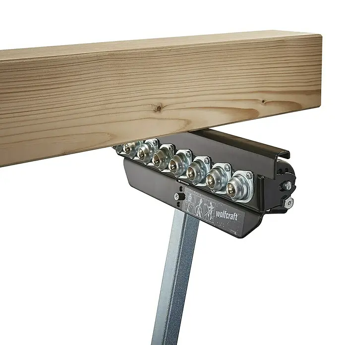 Wolfcraft Multifunktions-Auflagebock - Arbeitshöhe: 630 mm - 1.000 mm, Belastbarkeit: 50 kg - Nahaufnahme einer Wolfcraft Rollenauflage, die ein Holzbrett stützt. Ideal für Werkstätten, um schwere Materialien einfach zu bewegen.