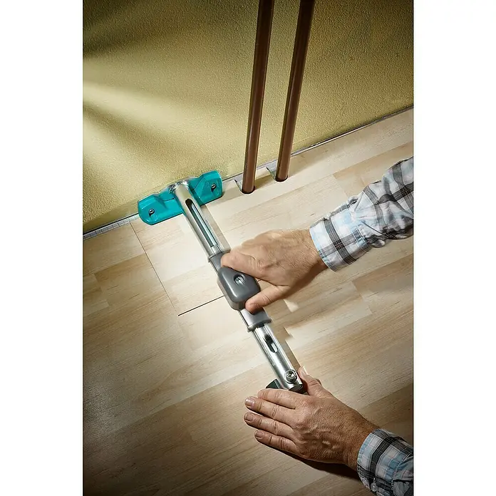 Wolfcraft Zugeisen - 410 x 170 x 80 mm, Metall - Eine Person benutzt ein Werkzeug zum Verlegen von Laminatboden in einem Raum mit Heizungsrohren.
