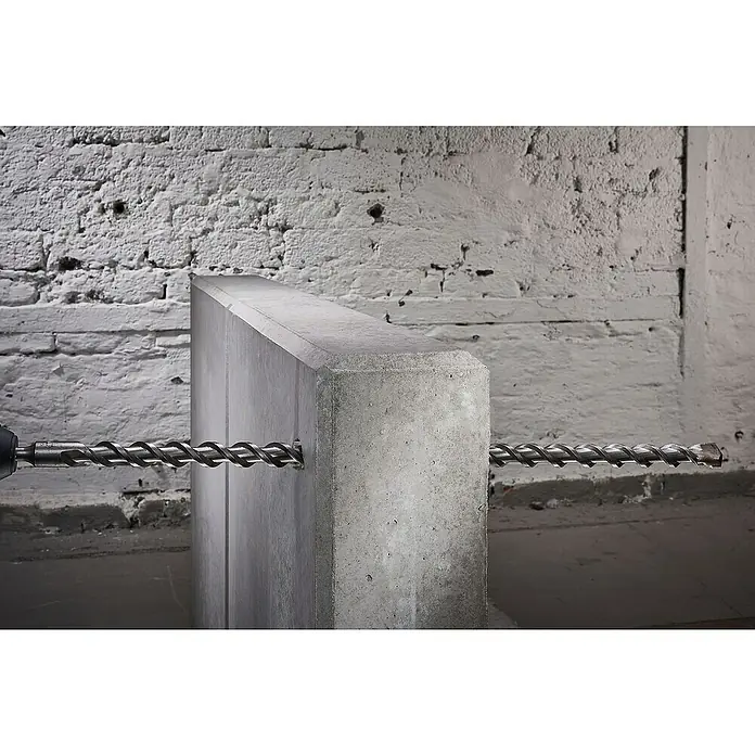 Wolfcraft Beton- & Steinbohrer Standard - Durchmesser Bohrer: 12 mm, Länge: 600 mm - Nahaufnahme einer Betonbohrmaschine, die durch einen grauen Betonblock bohrt, vor einem Wandhintergrund.