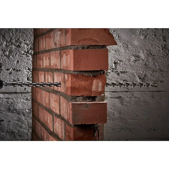 Wolfcraft Beton- & Steinbohrer Standard - Durchmesser Bohrer: 12 mm, Länge: 600 mm - Nahaufnahme eines Mauerbohrers, der durch eine Ziegelwand bohrt, Fokus auf die Bohrspitze und das Bohrloch.