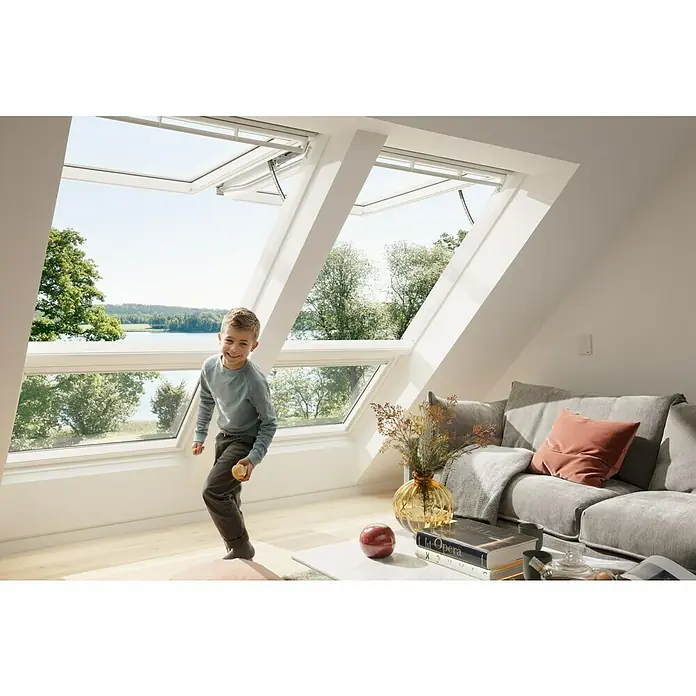 Velux Active Sensor Raumklima KLA 300 - Passend für: VELUX ACTIVE Starter-Set with NETATMO KIX 300 - Ein heller Dachraum mit VELUX Dachfenstern, die viel Tageslicht hereinlassen, während ein Kind im Raum spielt. Die Fenster bieten einen schönen Ausblick.