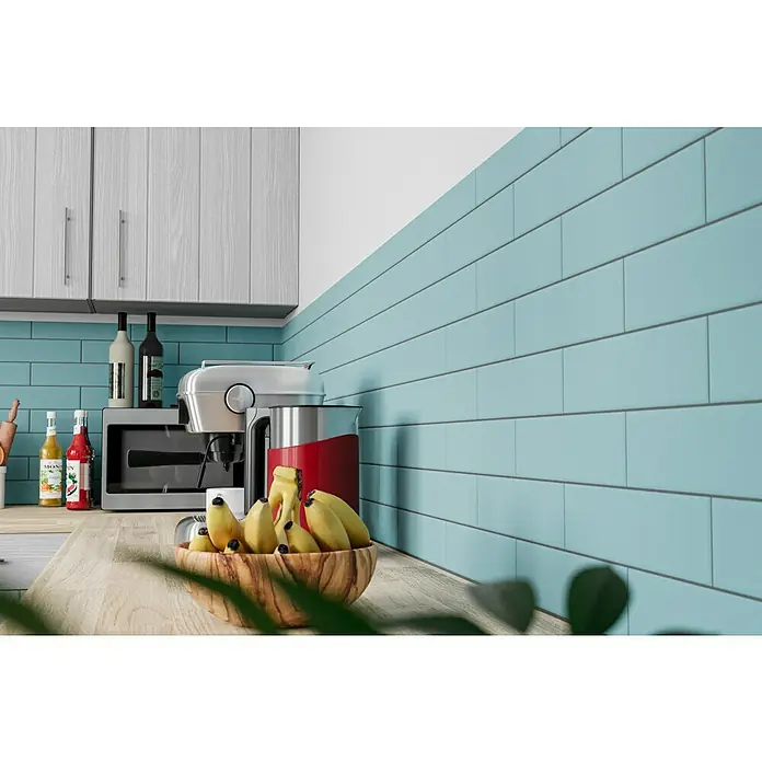 Modern Style Wandfliese Urban Aqua - 7,5 x 30 cm, Hellblau, Matt - Eine moderne Küche mit hellblauen Fliesen an der Wand, einem Holztisch und einem Holzkorb mit Bananen. Helle Küchenschränke.