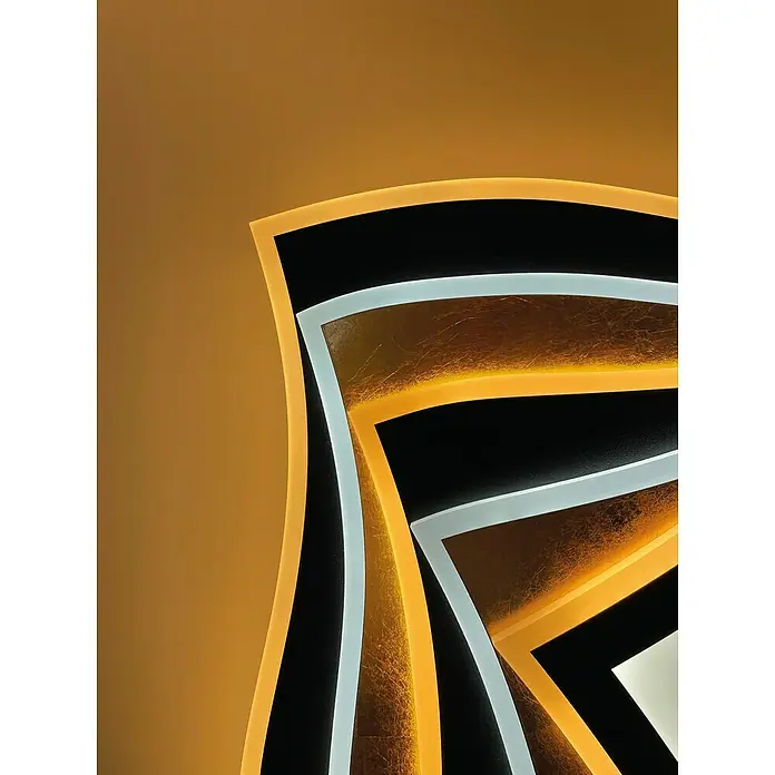 Fischer & Honsel LED-Deckenleuchte Hero - 50 W, L x B x H: 50 x 50 x 7,6 cm, Gold/Sandschwarz, Mehrfarbig - Nahaufnahme einer eleganten Deckenleuchte mit geschwungenen Formen in Gold, Schwarz und Weiß, die ein warmes Licht verbreitet.