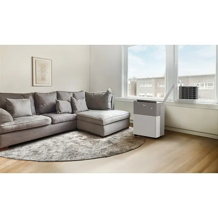 Midea Klimasplitgerät PortaSplit 12.000 Btu - Kühlleistung: 3.500 W, Heizleistung: 3.500 W, Raumgröße: 42 m² - Das Bild zeigt eine Midea Klimaanlage in einem modern eingerichteten Wohnzimmer. Die Klimaanlage steht am Fenster.