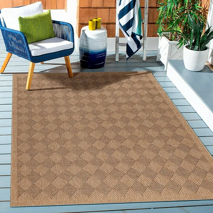 Outdoor-Teppich Dhaka IV - Schwarz, 150 x 80 cm, 100 % Polypropylen - Ein rechteckiger, brauner Teppich mit quadratischem Muster auf einer hölzernen Terrasse mit blauer Stufung, umgeben von Möbeln und Pflanzen.