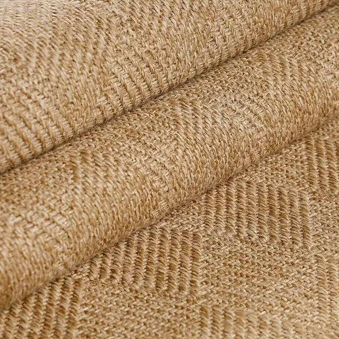 Outdoor-Teppich Dhaka VI - Beige, 150 x 80 cm, 100 % Polypropylen - Nahaufnahme eines gerollten Teppichs mit einem markanten Fischgrätenmuster in warmen, erdigen Farbtönen. Das Material wirkt robust und natürlich.