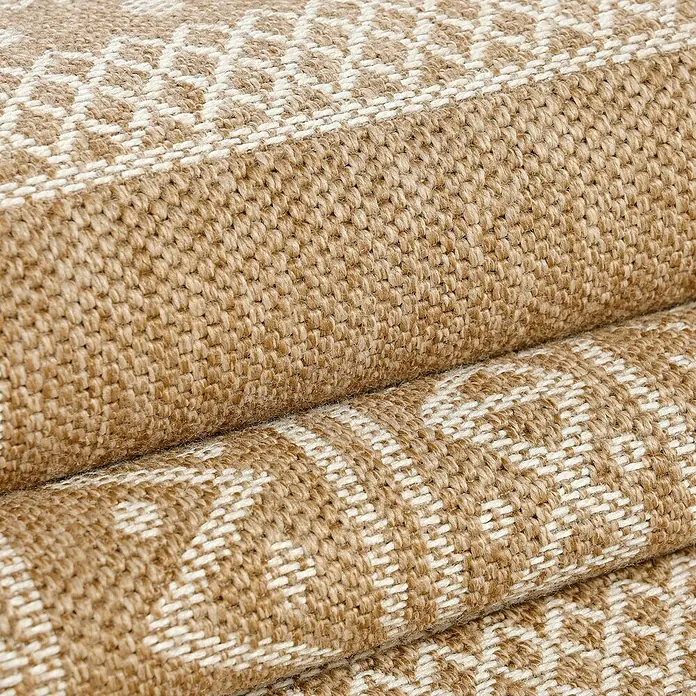Outdoor-Teppich Dhaka I - Beige, 250 x 80 cm, 100 % Polypropylen - Nahaufnahme eines Stapels hochwertiger Teppiche mit einem geometrischen Muster in Beige- und Cremetönen.