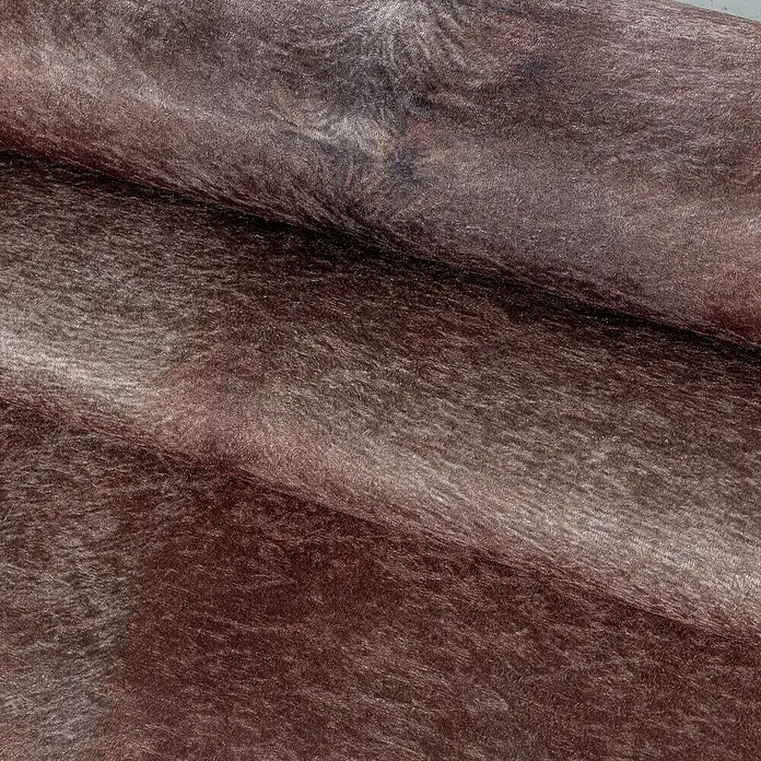 Flachgewebeteppich Etosha - Kuh, Braun, 200 x 150 cm, 100 % Polyester - Nahaufnahme von schimmerndem, braunem Leder, das Textur und Farbton hervorhebt.