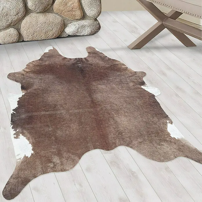 Flachgewebeteppich Etosha - Kuh, Braun, 200 x 150 cm, 100 % Polyester - Nahaufnahme einer Kuhfell-Teppich mit braunem und weißem Muster, der auf einem hellen Holzboden liegt.