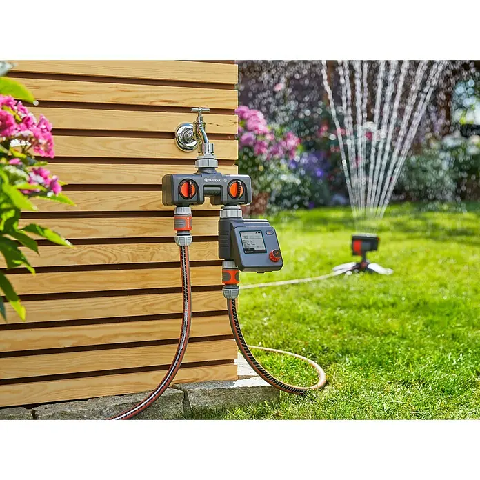 Gardena Bewässerungscomputer Select - Bewässerungsdauer: 1 min - 3 h - Gardena Bewässerungssteuerung mit zwei Ausgängen am Wasserhahn, angeschlossene Schläuche führen zu einem Rasensprenger im Garten.