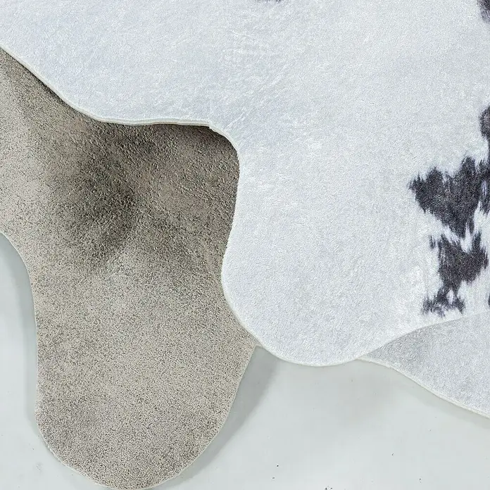 Flachgewebeteppich Etosha - Kuh, Braun/Weiß, 135 x 100 cm, 100 % Polyester - Nahaufnahme eines Kuhfellteppichs mit grauem und weißem Fellmuster, ideal für ein stilvolles und modernes Zuhause.