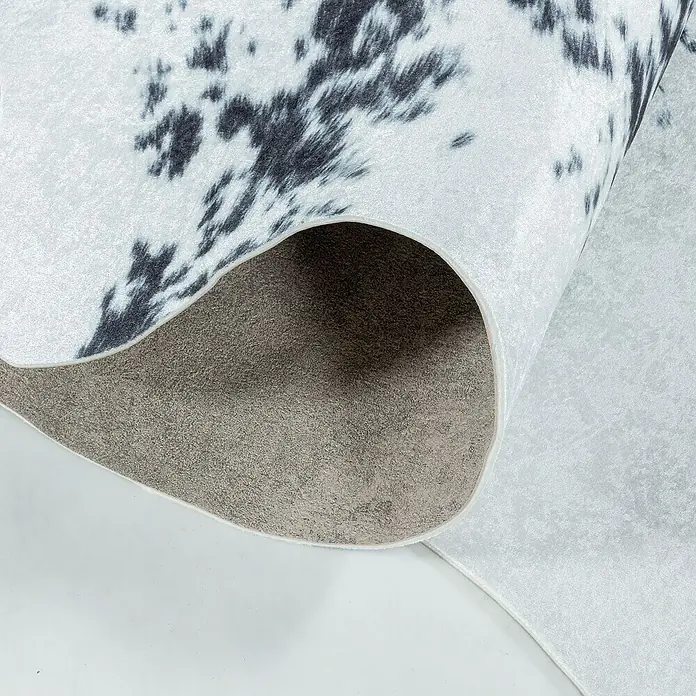 Flachgewebeteppich Etosha - Kuh, Schwarz/Weiß, 200 x 150 cm, 100 % Polyester - Detailaufnahme einer trendigen Kuhfell-Teppichrolle in Schwarz und Weiß, die eine stilvolle und moderne Note verspricht.