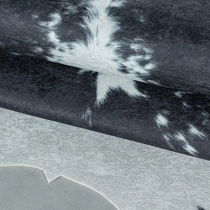 Flachgewebeteppich Etosha - Kuh, Schwarz/Weiß, 200 x 150 cm, 100 % Polyester - Nahaufnahme eines stilvollen Kuhfellteppichs in Schwarz und Weiß, der eine luxuriöse Textur und Muster zeigt.