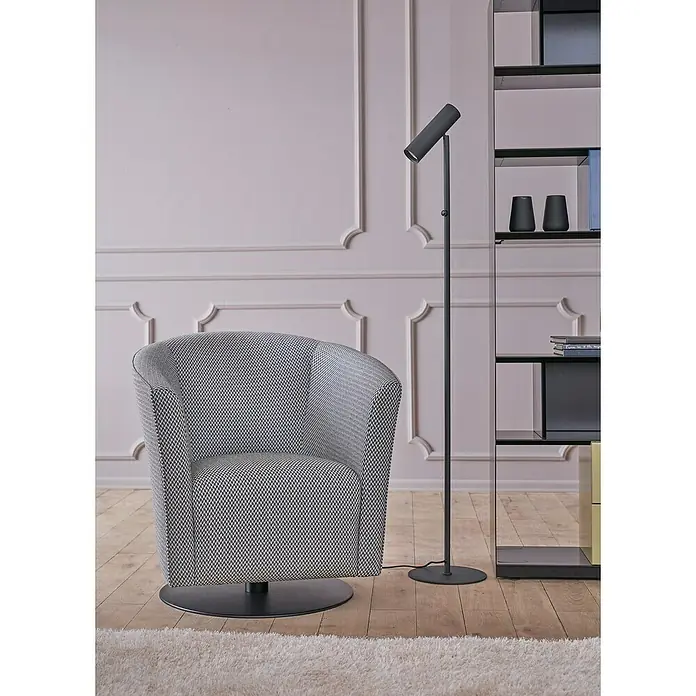 Nmc Decoflair Eckelement Eckteil Viertelbogen für Wandleiste - 4 Stk., Passend für: Nmc Decoflair Zierprofil Wandleiste CL1 - Ein grauer Sessel mit Muster steht neben einer Stehlampe und einem Regal, die das moderne Interieur ergänzen.