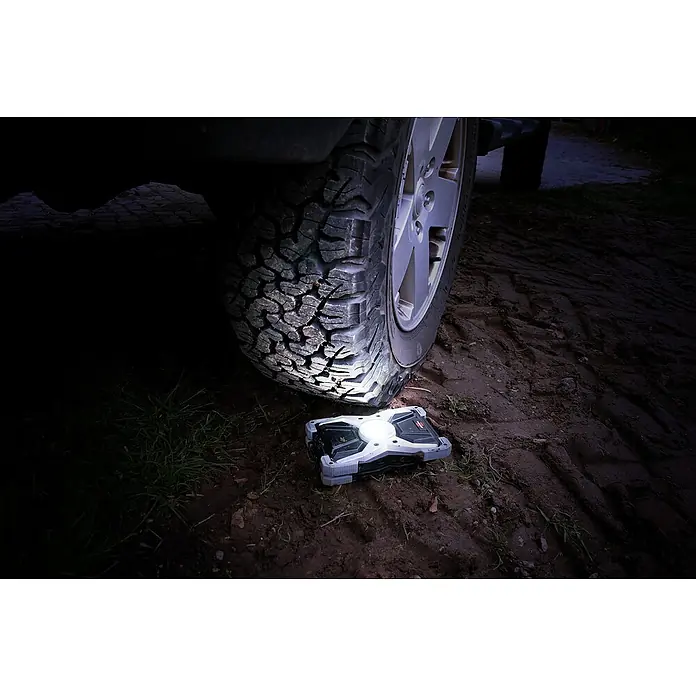 Brennenstuhl Mobiler LED-Strahler Rufus - Akkubetrieben, 30 W, L x B x H: 5 x 14 x 21 cm, IP65 - Das LED-Arbeitsleuchte leuchtet unter einem Auto, das auf einem Feldweg geparkt ist.