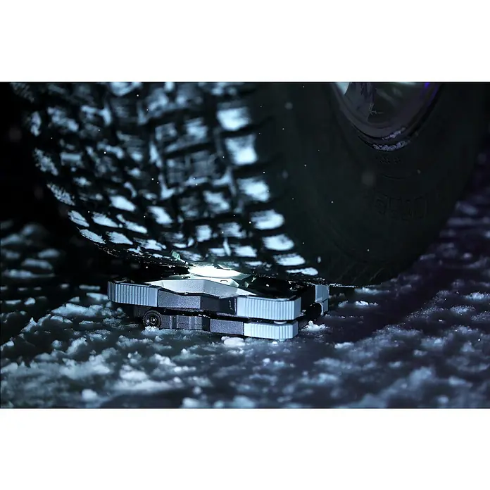 Brennenstuhl Mobiler LED-Strahler Rufus - Akkubetrieben, 30 W, L x B x H: 5 x 14 x 21 cm, IP65 - Nahaufnahme eines ATTO-Hebegeräts unter einem Reifen im Schnee, das für das sichere Anheben von Fahrzeugen konzipiert ist.