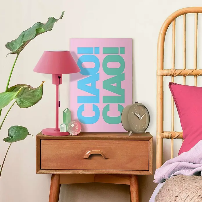 Reinders Leinwandbild Giclee on Canvas - Ciao Ciao, B x H: 20 x 30 cm - Nachttisch mit rosa Lampe, „Ciao!“-Poster, Wecker, Kristall und Pflanze. Das Poster hat einen rosa Hintergrund und die Schriftzüge sind blau und grün.