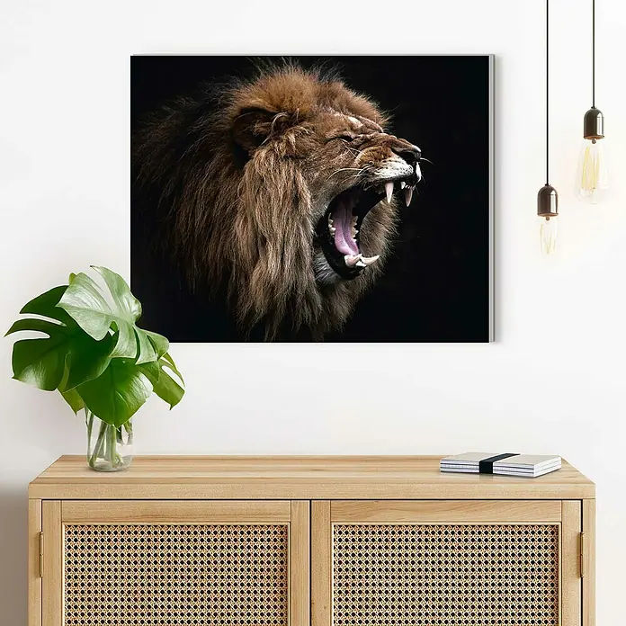 Reinders Decopanel - Roaring Lion, B x H: 50 x 40 cm - Ein quadratisches Gemälde eines brüllenden Löwen hängt über einem Sideboard mit einer Pflanze und Notizbüchern.