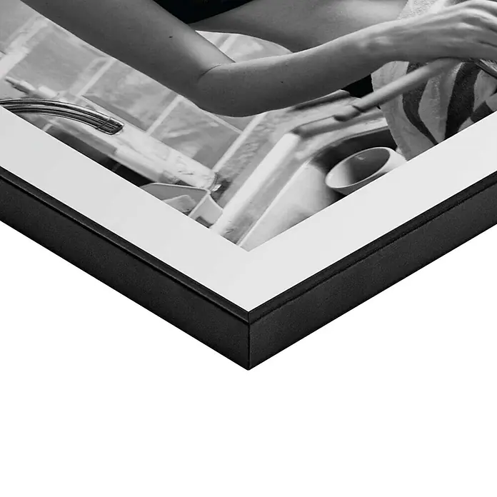 Reinders Bild Slim Frame Black - Pasta Lady, B x H: 30 x 40 cm - Schwarzer Bilderrahmen mit weißem Passepartout, das ein Schwarz-Weiß-Foto einer Person beim Geschirrspülen in der Küche zeigt.