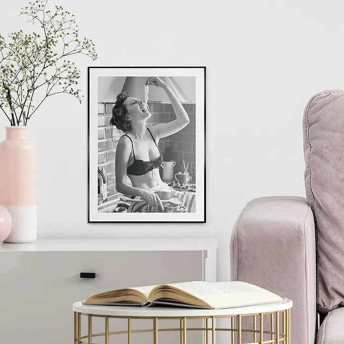 Reinders Bild Slim Frame Black - Pasta Lady, B x H: 30 x 40 cm - Schwarz-Weiß-Fotografie einer Frau mit Spaghetti in BH im Rahmen, die auf einem Sideboard in einem stilvollen Interieur platziert ist.