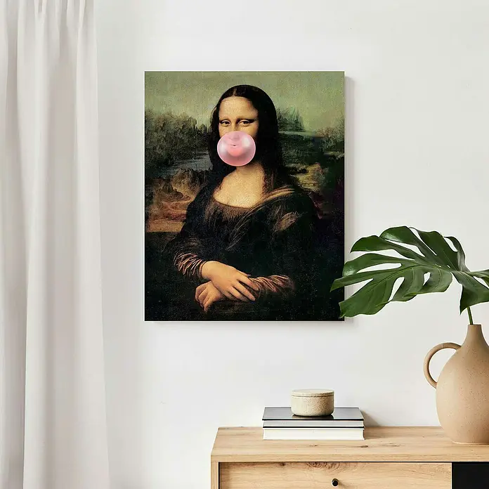 Reinders Decopanel - Mona Lisa Bubblegum, B x H: 40 x 50 cm - Wanddekoration: Mona Lisa Gemälde mit Kaugummi vor einem weißen Hintergrund, neben einer Kommode mit Dekoration.